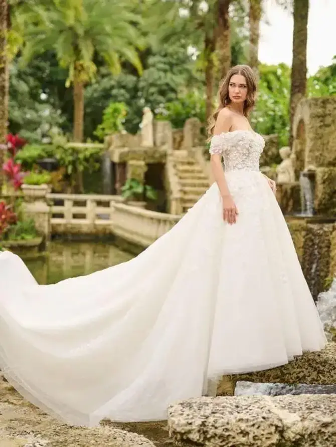 model is wearing a romantic off the shoulder ball gown wedding dress