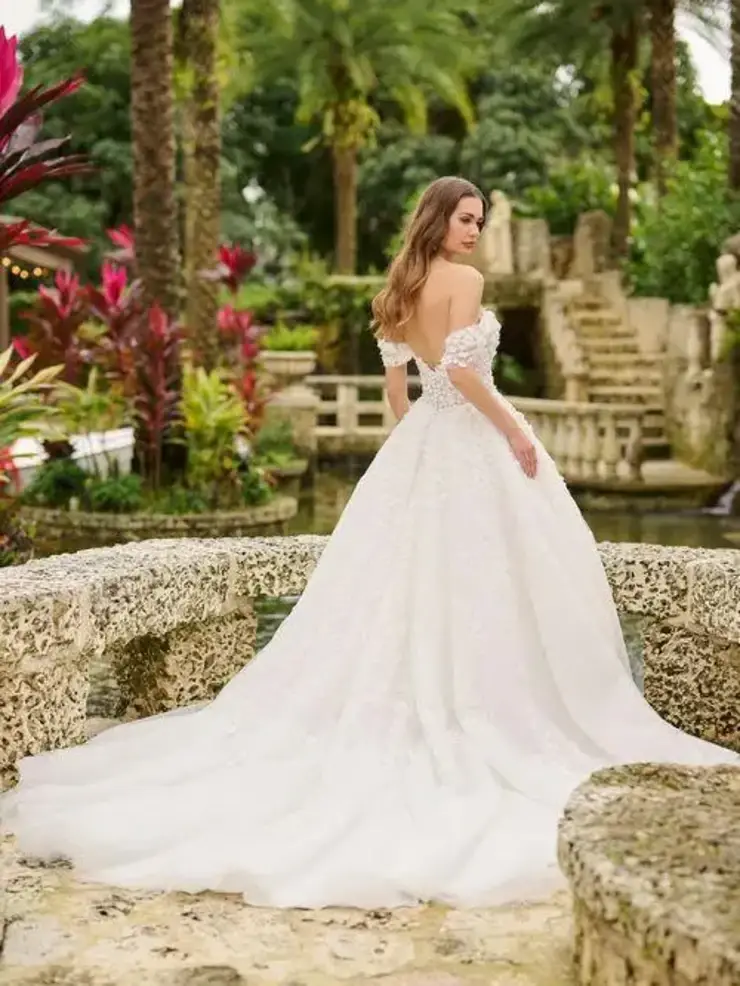 model is wearing a romantic off the shoulder ball gown wedding dress