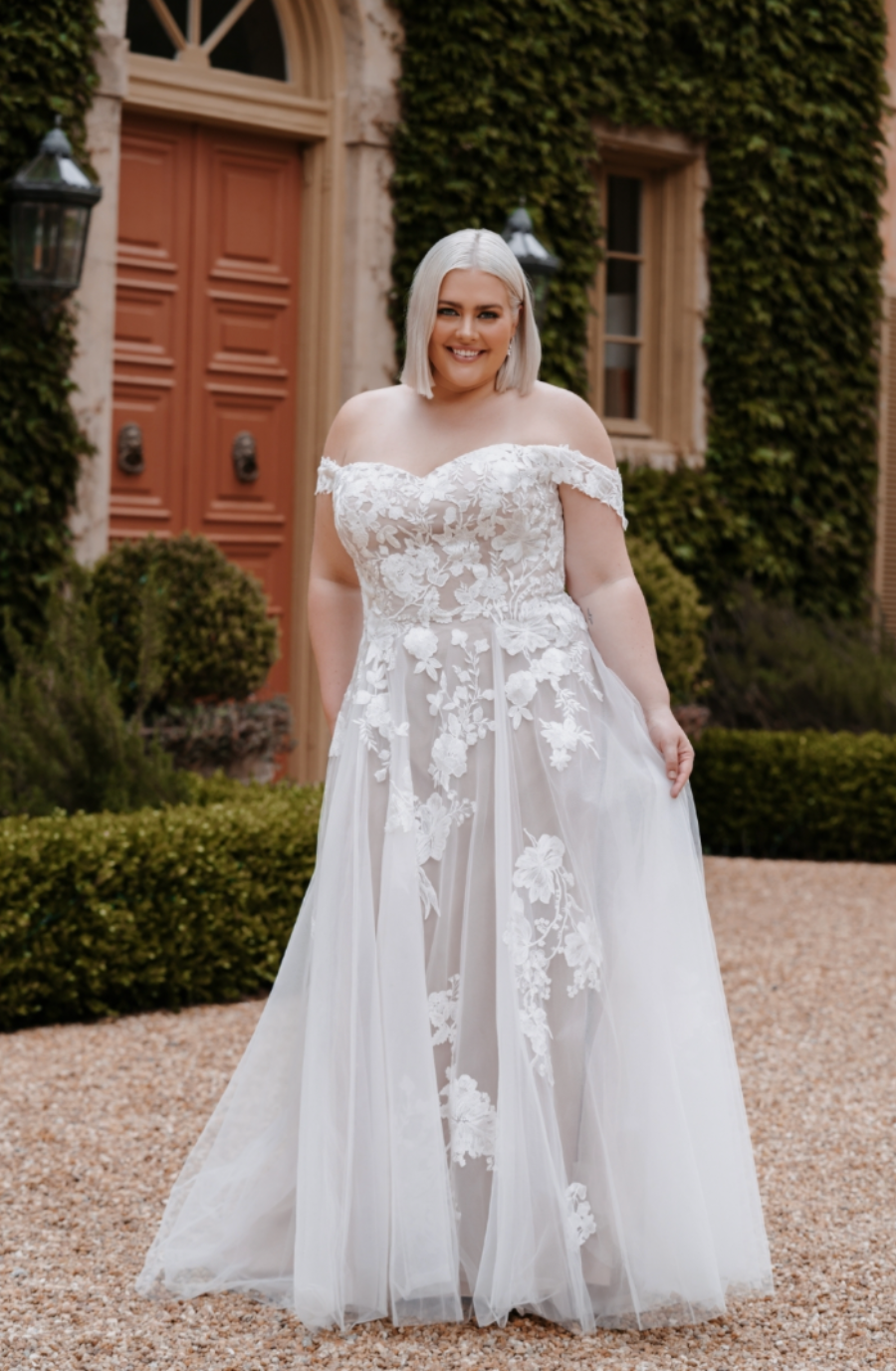 model is wearing an off the shoulder lace plus size wedding dress