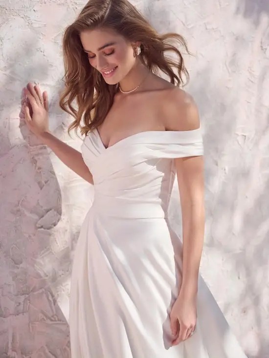Model is wearing an off the shoulder a-line wedding dress