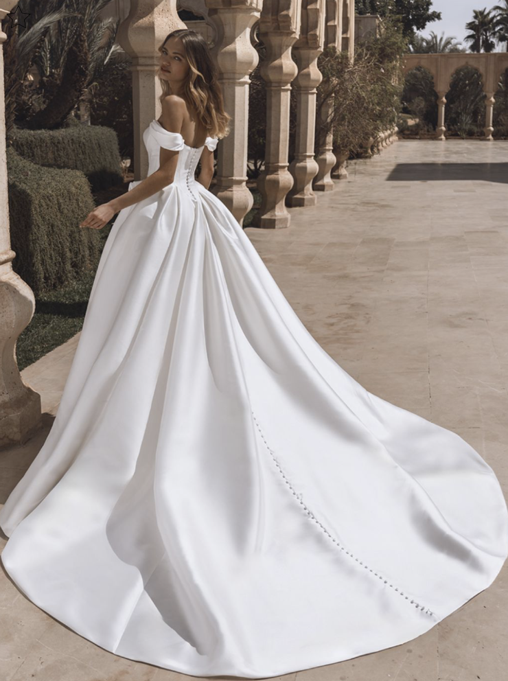 model is wearing an off the shoulder ball gown bridal dress