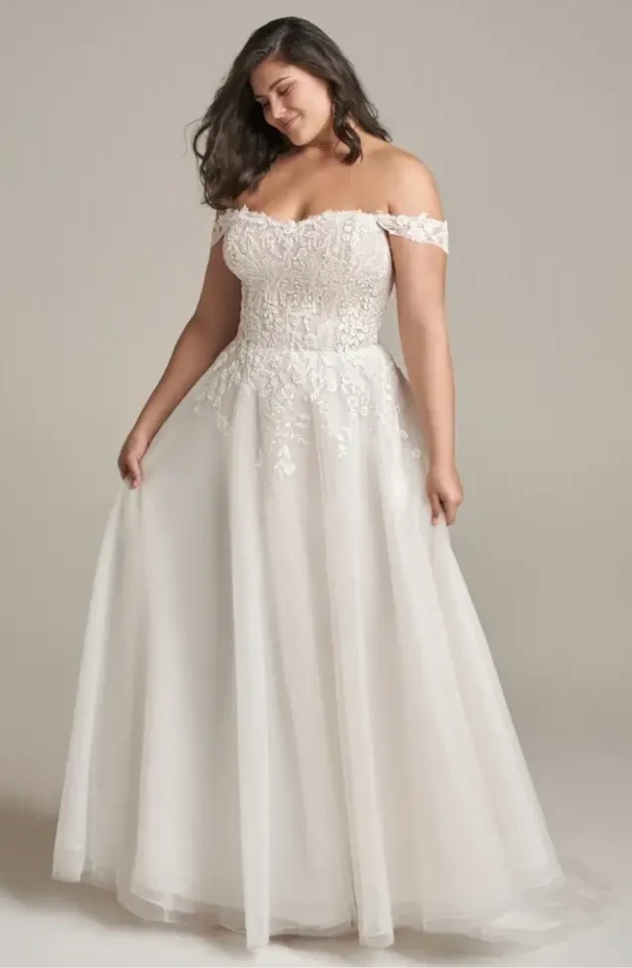 model is wearing an off the shoulder a-line bridal gown