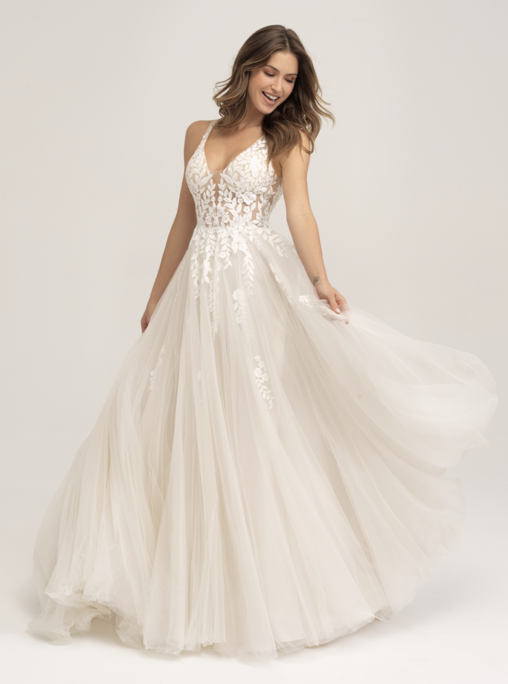 Model is wearing a soft A-line gown with a floral appliquéd illusion bodice, layered English net skirt, and an open scoop back
