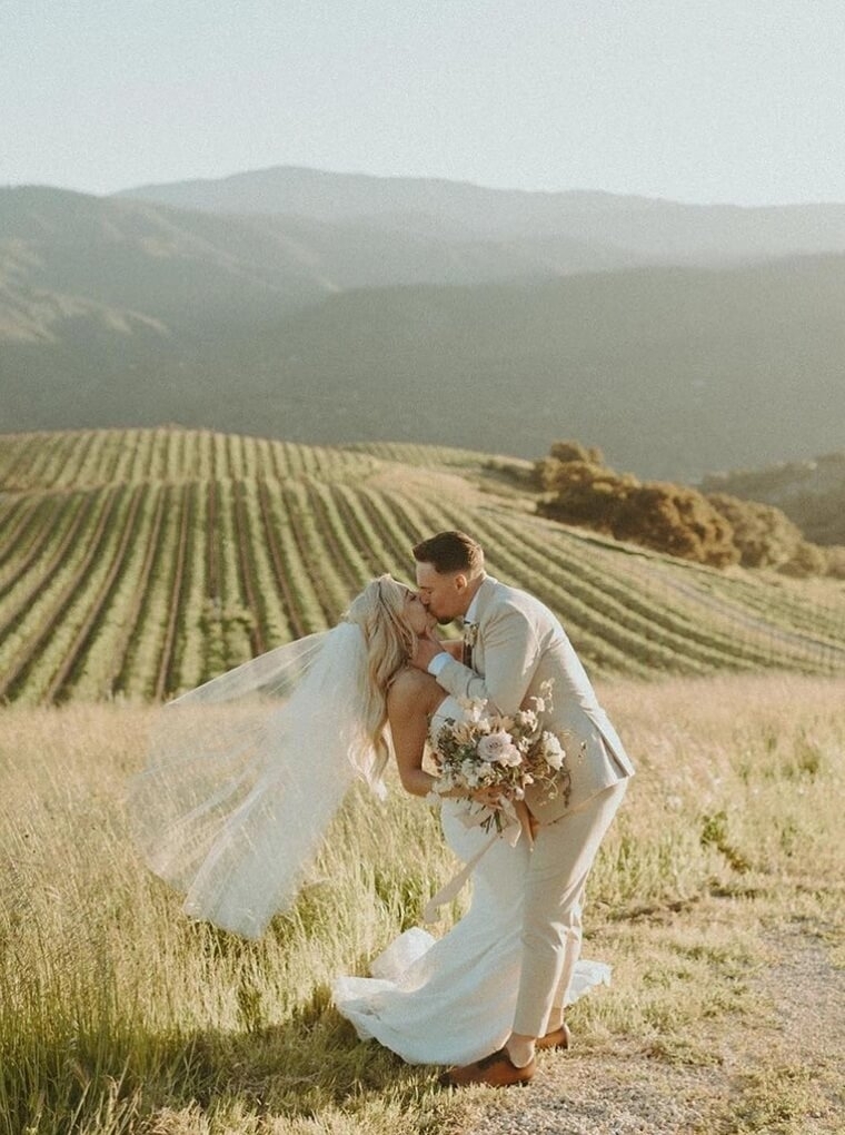 Сouple wearing a white gown and a white suit on the field