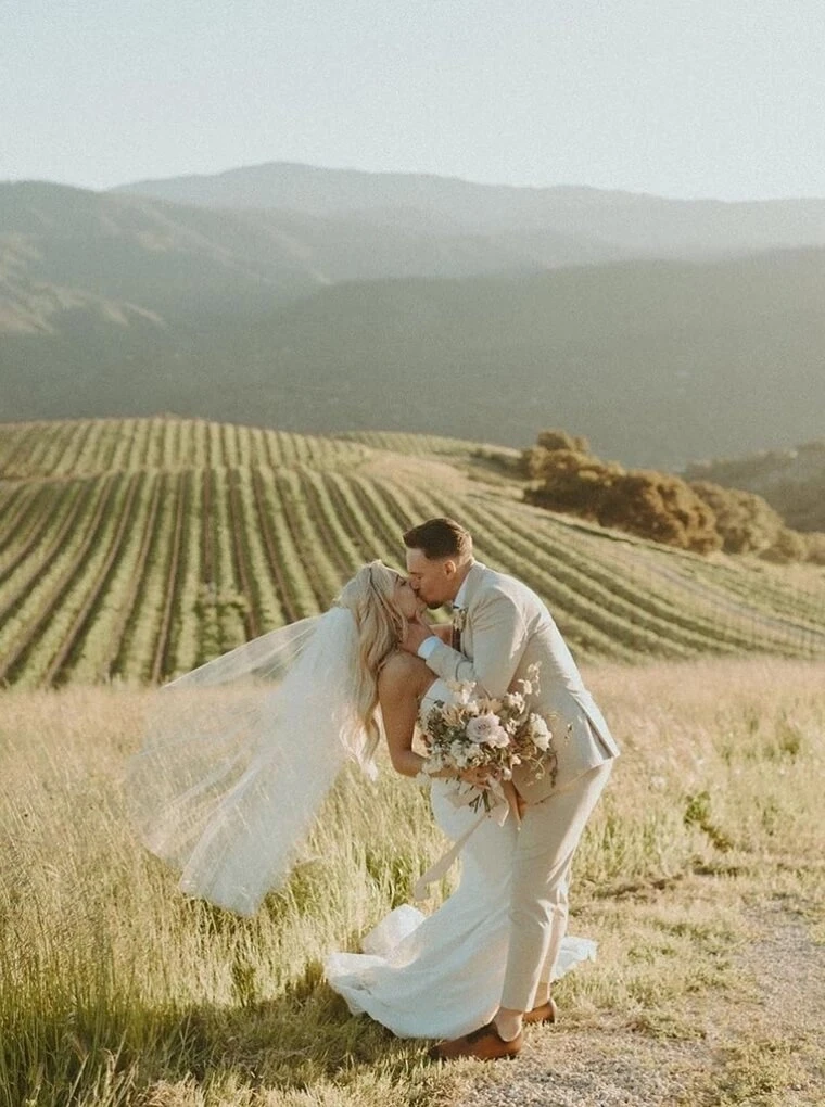 Сouple wearing a white gown and a white suit on the field
