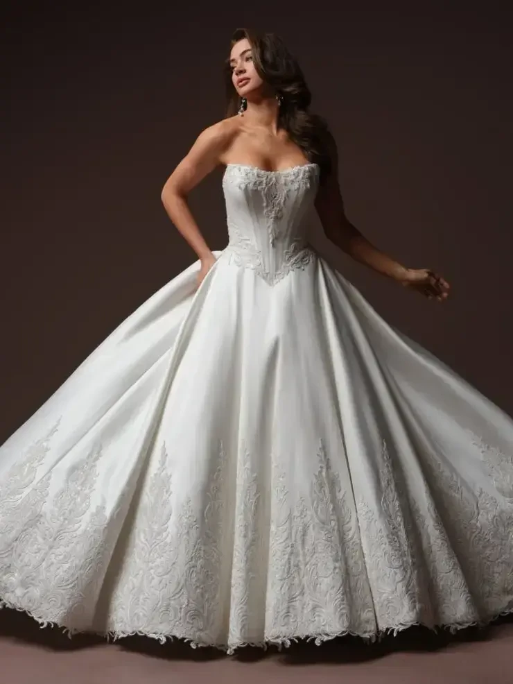 A woman wearing a strapless white wedding gown with a full skirt and intricate lace detailing.