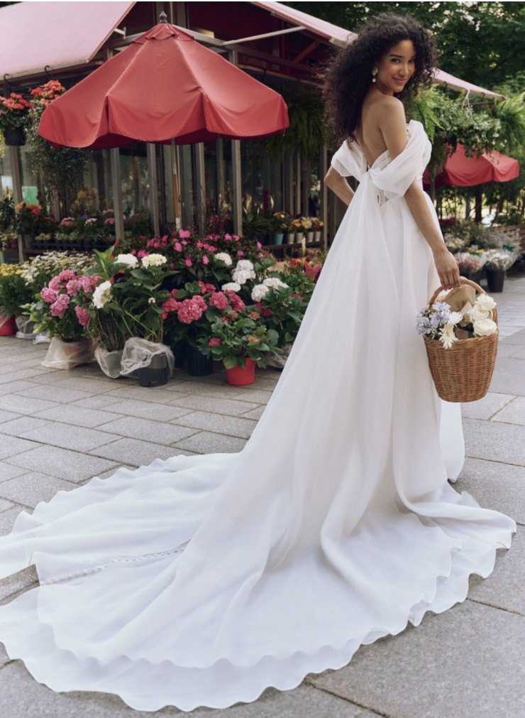 model is wearing an off the shoulder a-line bridal gown
